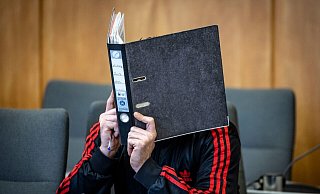 Der Angeklagte verbirgt im Essener Landgericht sein Gesicht hinter einem Aktenordner. - Christoph Reichwein/dpa