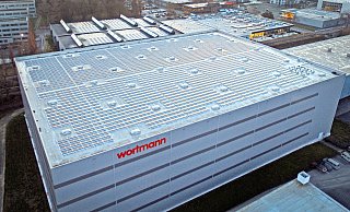Das Hochregallager mit Photovoltaik-Anlage (im Vordergrund) und die Hauptverwaltung mit Outlet (im Hintergrund).  - Wortmann Schuh-Holding