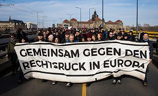 Gegendemonstranten ziehen mit einem Banner durch Dresden. - Foto: Oliver Killig/dpa-Zentralbild/dpa