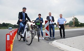 Bürgermeister Jürgen Schell, Conny Hagen von der Lebenshilfe sowie Tobias Fischer und Dietmar Stölting von „Straßen.NRW"  (von links) präsentieren am 22. Juni auf einem Pressetermin, dass sie mit dem Provisorium während der Bauzeit mehr Sicherheit für Radler bieten. - Katrin Kantelberg