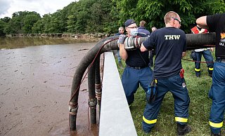 Helfer des Technischen Hilfswerks (THW) lassen Schläuche in die Steinbachtalsperre in Euskirchen hinab, um das Wasser abzupumpen. Der Damm der Talsperre droht einstürzen. - Marius Becker/dpa