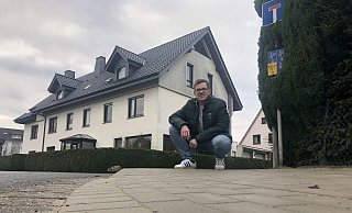 André Schielmann kniet an einem abgesenkten Bordstein am Sperlingsweg, für den er sich eingesetzt hatte.  - Sven Kienscherf
