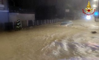 Auf einer überfluteten Straße treibt ein Auto in Kalabrien durch die Wassermassen. - Vigili del Fuoco/dpa Auf einer überfluteten Straße treibt ein Auto in Kalabrien durch die Wassermassen. - Vigili del Fuoco/dpa