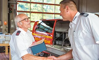 Der kommissarische stellvertretende Leiter der Feuerwehr Bad Salzuflen, Christian Drewes, dankt Reinhold Wiesekopsieker für seine 50-jährige Treue zur Feuerwehr. - FreitagTV