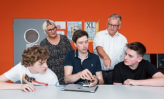 Annett Schmid von der Gebäudewirtschaft der Stadt Lemgo und Thomas Hahn von den Stadtwerken Lemgo (hinten) präsentieren mit Lehrer Jegor Rogalsky und den MWG-Schülern Mattis und Enrico-Michael Technik, die beim Reduzieren von CO2-Emissionen hilft. - Michael Reimer