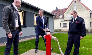 Mit Inbetriebnahme des Hydranten gilt das Feuerwehrgerätehaus offiziell als übergeben. Wilhelm Luft vom Architekturbüro Schmidt (links), Bürgermeister Jörg Bierwirth und Marc Tegeler, Einheitsführer Wöbbel, freuen sich. - Rudi Rudolf