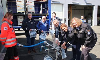 Wasser, marsch: Christiane Vieweger (Leiterin THW-RegionalstelleBielefeld), Sabine Beine, Thomas Lammering, Dr. Kerstin Ahaus (LeiterinGesundheitsamt), Dirk Kuchenbecker und Meinolf Haase (LeiterBevölkerungsschutz, von rechts) lassen sich von Jennifer Röder vomDRK-Ortsverein Detmold zeigen, wie an einer Ausgabestelle das gereinigte Wasserin Fünf-Liter-Beutel abgefüllt wird. - Kreis Lippe