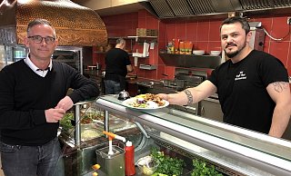 Yol-Chef Serafettin Yilmaz reicht Dennis Bernat von der Heilpädagogisch-therapeutischen Einrichtung Grünau einen Teller mit Essen. Am kommenden Mittwoch gehen alle Gewinnen aus dem Tagesverkauf an die Einrichtung. - Sven Kienscherf