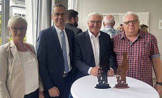 Jürgen Koch (rechts) überreicht Bundespräsident Frank-Walter Steinmeier (Zweiter von rechts) beim Imbiss in der Alten Schule in Brakelsiek den ersten Ziegler im Miniformat. Bürgermeister Jörg Bierwirth und Gattin Astrid gefällt der Prototyp auch gut. - Silke Buhrmester