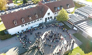 Mit einer Menschenkette umrahmen die Gegner der Schulschließung in Alverdissen das Gebäude. Aus der Luft macht eine Drohne Aufnahmen. - Sylvia Frevert
