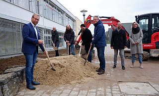 Bürgermeister Borris Ortmeier (von links), Andreas Wilde (Vorsitzender Ausschuss für Schule, Soziales und Generationen), Henning Waltermann (stellvertretender Vorsitzender Ausschuss für Bauen, Klimaschutz und Umwelt), Christian Olschweski (Vorsitzender Ausschuss für Bauen, Umwelt und Klimaschutz), Markus Tackenberg (stellvertretender Schulleiter), Chris Hüte-Getboga (Leiter Bauen, Soziales und Ordnung) und Caroline Reil (stellvertretende Vorsitzende Ausschuss für Schule, Soziales und Generationen) beim symbolischen ersten Spatenstich. - Lorraine Brinkmann