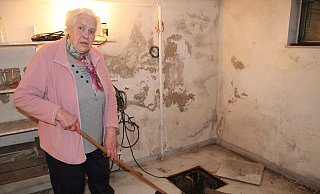 Inge Kronshage muss mehrmals täglich in den Keller gehen, um mit der Flitsche das Wasser in den Pumpensumpf zu schieben. Die Feuchtigkeitsschäden an der Wand sind unübersehbar. - Dieter Asbrock Inge Kronshage muss mehrmals täglich in den Keller gehen, um mit der Flitsche das Wasser in den Pumpensumpf zu schieben. Die Feuchtigkeitsschäden an der Wand sind unübersehbar. - Dieter Asbrock