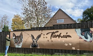 Künstler Maik Enge zeigt das Kunstwerk, das er auf dem Zaun des Franziskushofs gestaltet hat. - Fotorechte: Tierheim Franziskushof Künstler Maik Enge zeigt das Kunstwerk, das er auf dem Zaun des Franziskushofs gestaltet hat. - Fotorechte: Tierheim Franziskushof