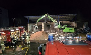Gemeinsam mit Mitarbeitern des Entsorgungsbetriebes Freise hat die Augustdorfer Feuerwehr am Montagabend brennenden Metallschrott gelöscht. Mithilfe eines Baggers und mehrerer Radlader wurde das Brandgut auseinandergezogen und anschließend durch Feuerwehr gekühlt und abgelöscht. - Feuerwehr Augustdorf