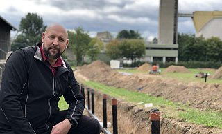 Projektleiter Daniel Steube von den Stadtwerken zeigt eine der Fernwärmeleitungen der neuen Solarthermie-Anlage am Klärwerk (rechts im Hintergrund). Auf der Fläche soll mit Hilfe der Sonnenenergie ab kommendem Jahr Energie gewonnen werden.  - Till Brand