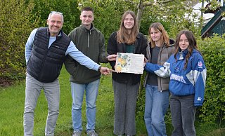 Jahrgangsstufenleiter Michael Heitkämper sowie die Klassensprecher Mathilda Krone, Pauline Thies, Mia Gruber und Finlay Winter (von links) präsentieren die Infotafel zur Goldrenette Freiherr von Berlepsch. - BUND Lemgo
