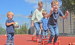 Früh übt sich: Zuschauer Liam (v.l.), Mama Nicole mit Luca (3) und Levi (5) hüpfen im Schlusssprung über kleine Hürden - eine Übung aus dem Anfängertraining der Handballer, die man auf dem Sportfest ausprobieren konnte. - Sibylle Kemna