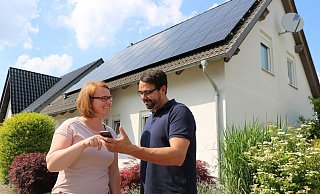 Jennifer Sonneborn und ihr Partner René Beermann prüfen auf dem Handy, was ihre PV-Anlage auf dem Dach im Hintergrund gerade an Strom produziert. - Alexandra Schaller