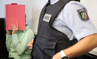 Die Angeklagte verdeckt beim Prozessauftakt ihr Gesicht mit einem roten Aktendeckel. - Holger Kosbab Die Angeklagte verdeckt beim Prozessauftakt ihr Gesicht mit einem roten Aktendeckel. - Holger Kosbab
