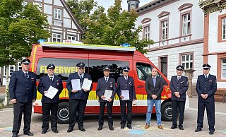 Feuerwehr-Chef Joachim Hartfelder, die Geehrten Maik Lohmeier-Feuerwehrchef Joachim Hartfelder, Maik Lohmeier-Schaeffer, Markus Rißmann, Marcel Blinne, Edgar Finke, Bürgermeister Christoph Dolle sowie die stellvertretenden Wehrführer Heiko Mühlenmeier und Cord Finke (von links) vor dem neuen Einsatzwagen am Rathaus. - brink-medien