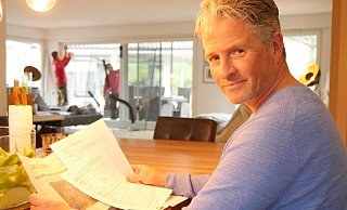 Gunnar Altenfeld mit dem Schadensersatzantrag und dem LZ-Artikel, der ihn auf Möglichkeit der Manöverschadensregulierung hinwies. Im Hintergrund tauschen die Fensterbauer Carsten Pape und Sebastian Leszczynski die Scheibe, auf der die Risse notdürftig mit Klebeband gesichert sind. - Jost Wolf