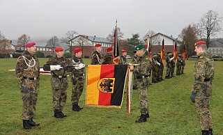 Hohe Auszeichnung: Divisionskommandeur Heico Hübner (Bildmitte) befestigt das Fahnenband „Einsatz“ an der Truppenfahne des Panzerpionierbataillons 1 aus Holzminden. Brigadekommandeur Stephan Willer (rechts) freut sich über die Ehrung der Bataillone der Panzerbrigade 21. - Bundeswehr / Nicolai Ulbrich