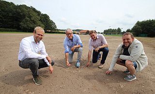 Passt der Boden? Das prüfen (von links) Bürgermeister Borris Ortmeier, TBV-Jahn-Vorsitzender Thomas Schwekendiek, Landtagsabgeordneter Jürgen Berghahn und Vereinsmitglied Timo Konieczny und lassen sich vom Starkregen-Zwischenfall die gute Laune nicht verderben. - Jens Rademacher