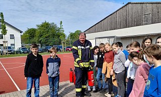 Bei der Station der Freiwilligen Feuerwehr erklärt ein Feuerwehrmann den Kindern, wie sie ein Feuer löschen können. - Franka Ronkartz (LZ)