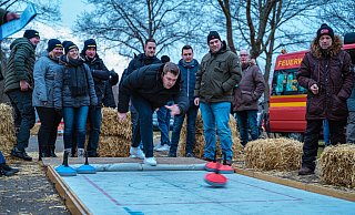 Zielsicherer Wurf: Florian Duda von Team der „hauptamtlichen Kräfte“ setzt an und feuert den Eisstock über die Plane. Im Hintergrund drücken Jannik Wiesekopsieker, Timo Wessel und Stefan Johannsmeyer (von links) die Daumen. Das Team vom „Löschtrupp Holzhausen“ links zittert mit. - FreitagTV/Stock Zielsicherer Wurf: Florian Duda von Team der „hauptamtlichen Kräfte“ setzt an und feuert den Eisstock über die Plane. Im Hintergrund drücken Jannik Wiesekopsieker, Timo Wessel und Stefan Johannsmeyer (von links) die Daumen. Das Team vom „Löschtrupp Holzhausen“ links zittert mit. - FreitagTV/Stock