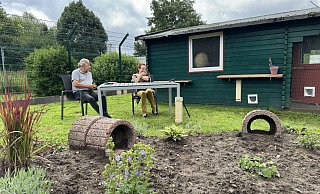 Stefan Quirini und Dorothee Stiegemann sitzen an einem Tisch im Katzenauslauf. Im Arm hält Stiegemann für das Foto eine "zahme" Katze, die verwilderten Katzen lassen sich für das Foto nicht blicken. - Sven Kienscherf