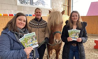 Stellen die Broschüre vor: (von links) Jasmin Baier, Tourist-Information Schieder-Schwalenberg, Anna-Lea Schaper, Reiterhof „Hestatimi Islandpferde", Larissa Gräbner, Tourist-Information Lügde, auf dem Reiterhof „Hestatimi Islandpferde" in Harzberg.  - ©Schieder-Schwalenberg