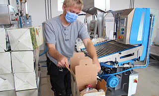 Werner Klemme packt die Beutel mit hei&szlig;em Apfelsaft in Kartons. - Nadine Uphoff