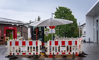 Bauarbeiter reparieren am Dienstag Schäden an einer Internet-Kupferleitung an der Klingenbergstraße. Den wiederkehrenden Regenschauern trotzen sie mit einem Sonnenschirm über der Grabungsstelle. - Raphael Bartling