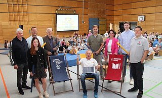 Friedhelm Susok (Mitte, sitzend) stimmt die Kinder und die Erwachsenen auf den Energieunterricht ein. Passend dazu hat er eine Solarzelle dabei. Mit dabei (von links) Thomas Grundmann (Schulleiter der Grundschule Knetterheide), Gina Wattenberg (Stadtwerke Lemgo), Tobias Priß (Kreis Lippe), Jürgen Georgi (Umweltstiftung Lippe), Stefan Schöbel (Blomberger Versorgungsbetriebe), Eva Ellminger (Stadtwerke Detmold), Moritz Sibma (Stadtwerke Bad Salzuflen) und Michael Makosch (Stadtwerke Oerlinghausen). - Kreis Lippe