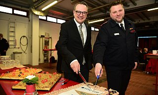 Bürgermeister Markus Baier und Stadtjugendfeuerwehrwart Christian Heidemann schneiden den Jubiläumskuchen an - Nicole Ellerbrake