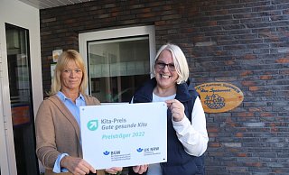 Manja Fischer (links) und Kita-Leiterin Elke Schlepphorst zeigen das Schild, das belegt, wofür das Familienzentrum Kita Spatzennest ausgezeichnet worden ist. - Birgit Guhlke