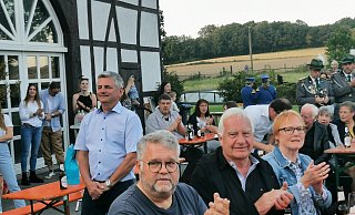 Kommunalpolitiker Jobst-Dieter Rodewald-Tölle (Mitte stehend) nimmt inmitten von geladenen Gästen aus Politik und Verwaltung gerührt die feierliche Verabschiedung aus dem politischen Leben im Rahmen eines Großen Zapfenstreiches auf seinem Hof in Selbeck entgegen. - Sylvia Frevert