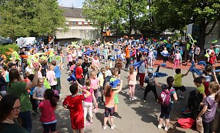 Zum Abschluss eines besonderen Bewegungstages versammeln sich Schüler und Lehrer auf dem Schulhof und schwenken zu lauter Musik ihre farbigen Westen.  - Birgit Guhlke