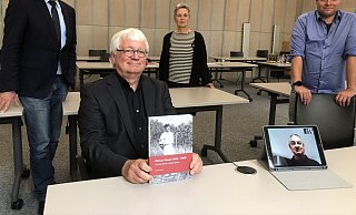 Aus Israel ist mit Michael Raveh (unten rechts auf dem Tablet) der Sohn von Shmuel und Ehrenbürgerin Karla Raveh zugeschaltet. Für seine Buchveröffentlichung zeigen sich im Ratssaal (von links) Bürgermeister Dr. Reiner Austermann, der frühere Museumsleiter Jürgen Scheffler, Kultur-Geschäftsbereichsleiterin Annette Paschke-Lehmann und Museums-Chef Fabian Schröder dankbar. - Till Brand