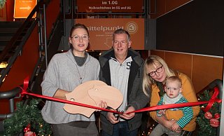 Jochen Dubbert duchschneidet das rote Band, während Rabea Kruel (links) das „Spendenschwein-Brettchen" und Claudia Beckmeier den kleinen Josse hält. - Judith Stracke