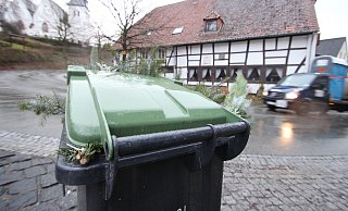 Günstiger: Die Gebühren für die Abfuhr von Rest- und Biomüll in Kalletal sinken. Das Foto zeigt eine grüne Tonne in Sichtweite von Altem Krug und Peterskirche in Talle. Foto: Jens Rademacher - Jens Rademacher