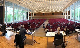 Der Rat tagt in den Weiten der Konzerthalle. Auf der Bühne hat der Verwaltungsvorstand Platz genommen. In den vorderen Reihen sitzen Ratsmitglieder. Im Hintergrund verfolgen Gäste das Geschehen. - Thomas Reineke Der Rat tagt in den Weiten der Konzerthalle. Auf der Bühne hat der Verwaltungsvorstand Platz genommen. In den vorderen Reihen sitzen Ratsmitglieder. Im Hintergrund verfolgen Gäste das Geschehen. - Thomas Reineke
