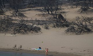Hinten die verbrannte Vegetation, vorn das Mittelmeer. Ein Strand bei Gennadi auf Rhodos. - Petros Giannakouris/AP Hinten die verbrannte Vegetation, vorn das Mittelmeer. Ein Strand bei Gennadi auf Rhodos. - Petros Giannakouris/AP