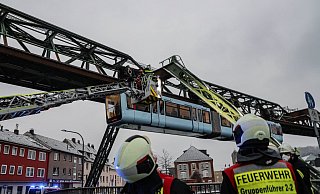 Einsatzkräfte der Feuerwehr befreien mit einer Drehleiter Fahrgäste aus einem Wagen der Schwebebahn, die wegen des eisigen Wetters stehen geblieben ist. - Foto: Christoph Petersen/dpa