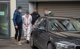 Polizisten bringen einen der Tatverdächtigen (im weißen Overall) nach dem Haftprüfungstermin am Landgericht Kaiserslautern aus dem Justizgebäude. - Foto: Harald Tittel/dpa