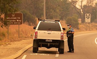 Die Polizei spricht bei einer Straßensperre auf der Great Northern Autobahn mit Anwohnern, die versuchen, in ihre Häuser zurückzukehren. - Foto: Richard Wainwright/AAP/dpa
