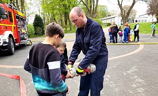 Der Leiter der Jugendfeuerwehr Hörste, Jan-Lukas Schlink, zeigt den Kindern bei einem Spielnachmittag am Kinderheim, wie man Schläuche miteinander verbindet. - Astrid Sewing