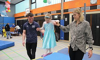 Die vierjährige Emilia balanciert als Prinzessin Elsa verkleidet auf der Slackline. Mama Piera Meier und Jannik Schalofsky vom TBV Jahn Alverdissen reichen ihr die Hand. - Nadine Uphoff