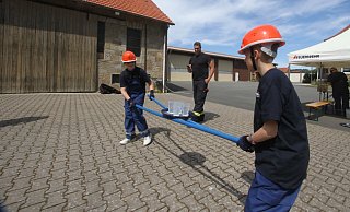 Auf einem Hof in Retzen müssen die Teilnehmer der Jugendfeuerwehr Bad Salzuflen ein Tablett mit Plastikbecher nur mit Hilfe von zwei Stangen ins Ziel befördern. Hier sind gute Absprachen und Geschick gefragt. - Daniel Hobein / Feuerwehr Bad Salzuflen Auf einem Hof in Retzen müssen die Teilnehmer der Jugendfeuerwehr Bad Salzuflen ein Tablett mit Plastikbecher nur mit Hilfe von zwei Stangen ins Ziel befördern. Hier sind gute Absprachen und Geschick gefragt. - Daniel Hobein / Feuerwehr Bad Salzuflen