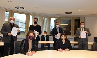 Die Grünen links, die Sozialdemokraten rechts: Fraktionsvorsitzender Werner Loke und Kreis-Parteisprecher Robin Wagener stehen hinter Kreissprecherin Dr. Inga Kretzschmar (vorne links), für die SPD unterschreibt die Kreisvorsitzende Ellen Stock. Hinter ihr stehen Fraktionsvorsitzender Henning Welslau und Landrat Dr. Axel Lehmann. Andreas Kuhlmann (SPD) unterzeichnet den Koalitionsvertrag als Mitglied der Landesverbandsversammlung. - Astrid Sewing